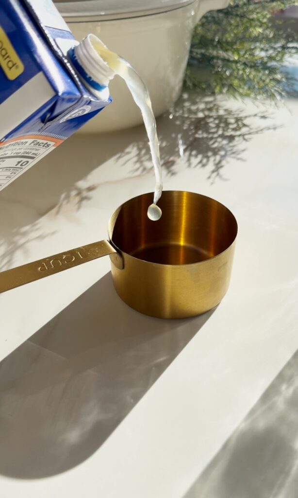 stir and gather pouring chicken broth for sheet pan tomato soup