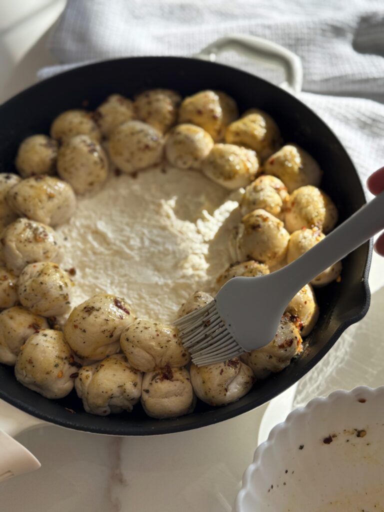 stir and gather brushing butter on pizza dip biscuit balls